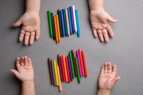 Many crayons of many different colors with kids hands. Top view Stock Photos
