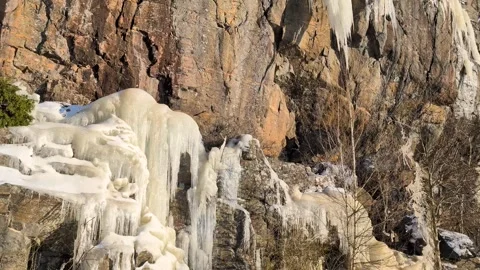 Many crowded massive icicles melting in the spring sun on a mountainside Video stock 331042029