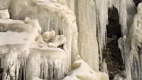 Many crowded massive icicles melting in the spring sun on a mountainside Stock-Footage 331042204
