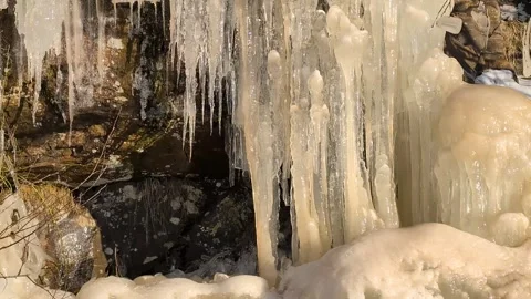 Many crowded massive icicles melting in the spring sun on a mountainside Stock Footage 331043496