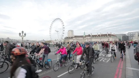 Many cyclists passing Westminster Bridge and London Eye Stock Footage 71061429