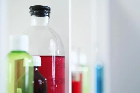 Many different bottles and test tubes with liquids of different colors stand on Foto stock
