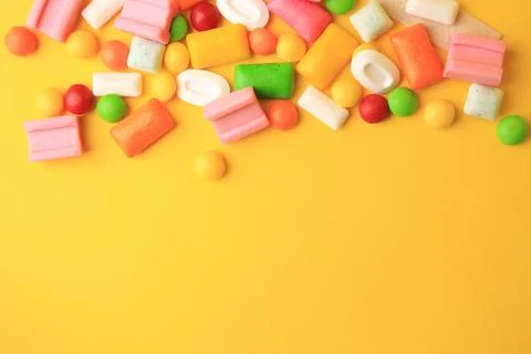 Many different chewing gums on yellow background, flat lay. Space for text Stock Photos