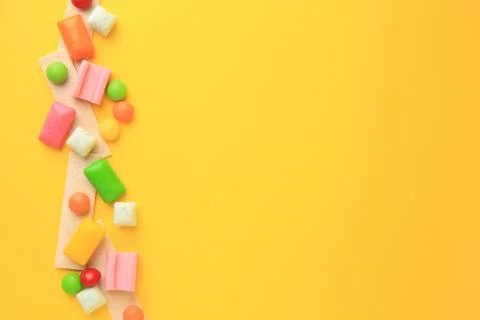 Many different chewing gums on yellow background, flat lay. Space for text Stock Photos