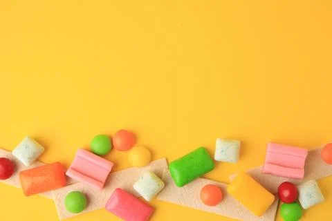 Many different chewing gums on yellow background, flat lay. Space for text Stock Photos
