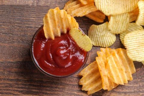 Many different chips with red sauce on a brown wooden table. Snacks. View fro Stock Photos