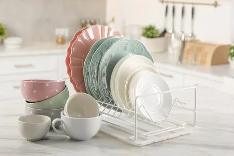 Many different clean dishware and cups on white marble table in kitchen Stock Photos