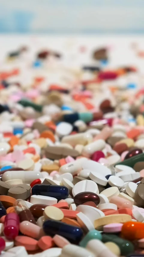 Many different colored pills are scattered on the white wooden table. Movem.. Stock Footage 291956367