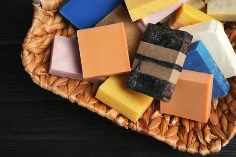 Many different handmade soap bars in wicker basket on table, top view Foto stock