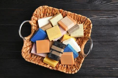 Many different handmade soap bars in wicker basket on table, top view Foto stock