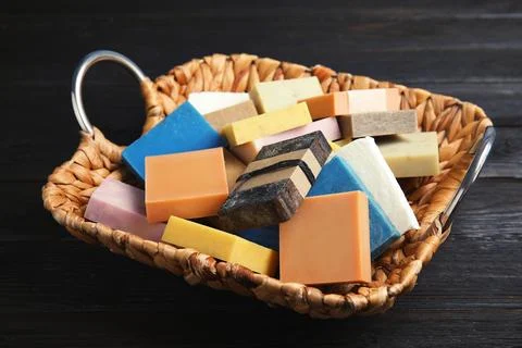 Many different handmade soap bars in wicker basket on table Foto stock
