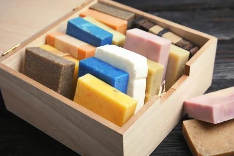 Many different handmade soap bars in wooden box on table, closeup Foto stock