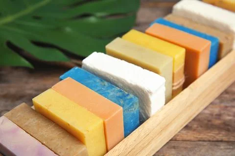 Many different handmade soap bars in wooden box on table, closeup Foto stock
