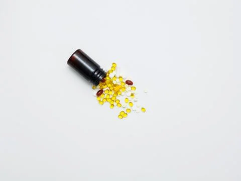 Many different multi-colored vitamins and pills poured from a plastic jar on a Fotos Stock