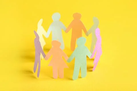 Many different paper human figures standing in circle on yellow background. D Stock Photos