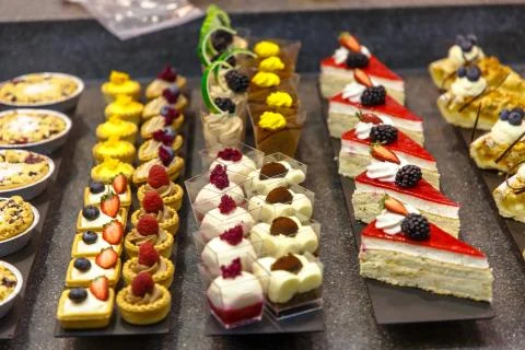 Many different small cakes are on the window of the candy shop. Stock Photos