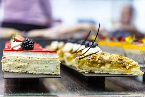 Many different small cakes are on the window of the candy shop. Stock Photos