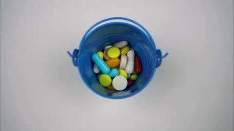 Many different tablets and capsules fill mini bucket, top view. Stop motion Stock Footage 241163873