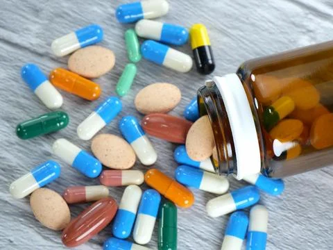 Many different types of medicines poured out of brown bottles on a white-gr.. Stock Photos