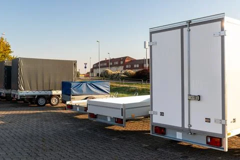 Many different types small passenger car cargo freight trailers parked in row at Stock Photos
