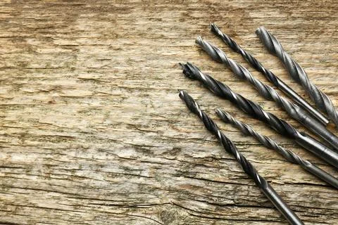 Many drill bits on wooden table, flat lay. Space for text Stock Photos