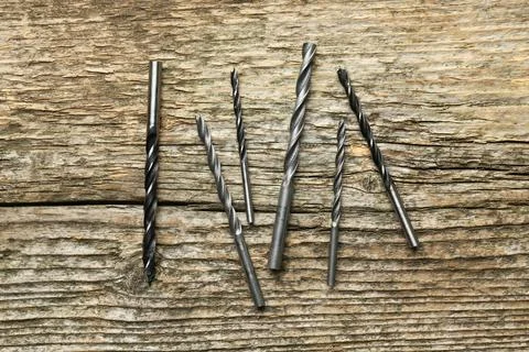 Many drill bits on wooden table, flat lay Stock Photos
