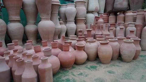 Many earthenware pots displayed on surface with greenery Stock Photos