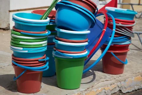 Many empty multi-colored plastic buckets stand near the entrance of building Stock Photos