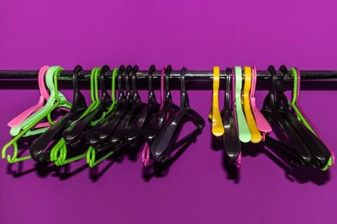 Many empty multi-colored plastic hangers hanging on a metal rack Stock-Fotos