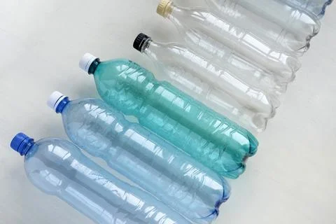 Many empty plastic bottles lie on a white table. plastic pollution Stock Photos