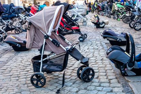 Many empty prams and child car safety seat parked on city street paving stone Foto stock