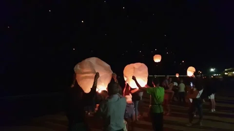 Many fire sky asian lanterns flying and tourists at beach party Stock Footage 280893109