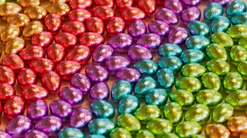 Many foil-wrapped chocolate eggs are arranged in rainbow color composition. Vídeos de archivo 201176351