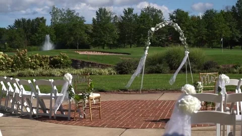 Many folding empty white wooden chairs stand in rows on the green lawn Stock Footage 187094302