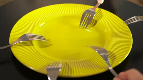 Many forks knocking on an empty yellow plate Stock Footage 330681448
