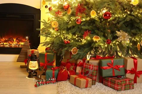 Many gift boxes, decorative elements and Christmas tree near fireplace at hom 스톡 사진