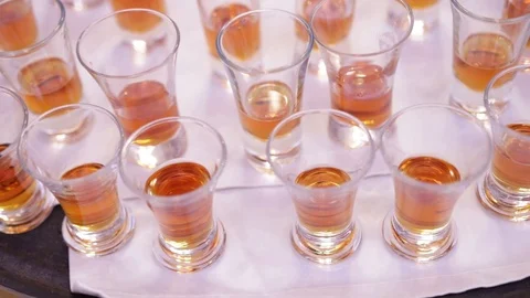 Many glasses filled with alcohol on a table with a white tablecloth Stock Footage 119818682