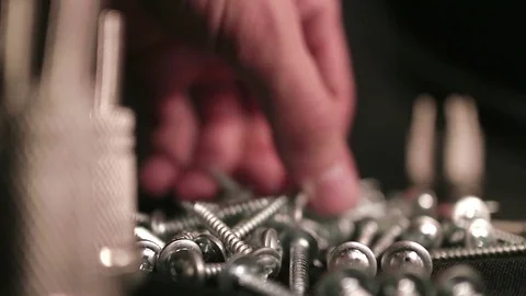 Many glossy screws close-up. The man takes the screws or throws them. Video in l Stock Footage 79753441