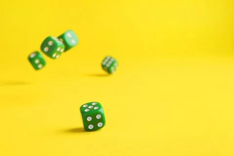 Many green game dices falling on yellow background. Space for text Stock Photos