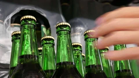 Many green glass bottles of beer on a store shelf and male hands take a couple Stock Footage 201588053