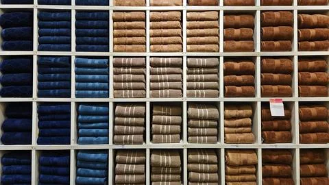 Many groups stack blue, brown, gray, or grey towels on a white wooden shelf Stock Photos