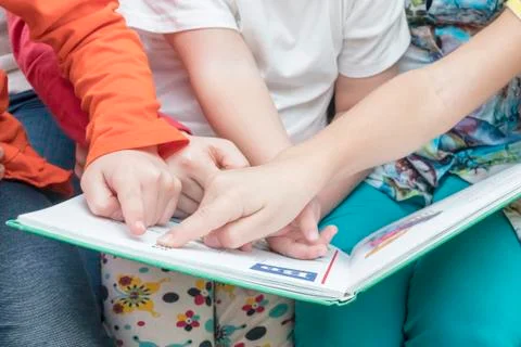 Many hands point into a book Stock Photos