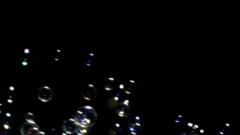 Many illuminated soap bubble floating in black background Stock Footage 79473377