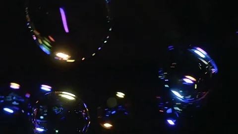Many illuminated soap bubble floating in black background Stock Footage 79517996
