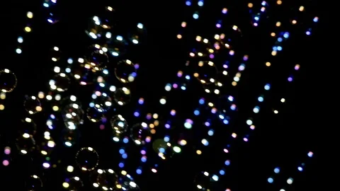 Many illuminated soap bubble floating in black background Stock Footage 79584045