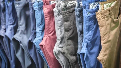 Many jeans hanging on arack. Row of pants denim jeans hanging in closet, conc Stock Photos