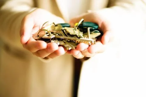 Many keys in hands on light background. Sunny morning light. Copy space Stock Photos