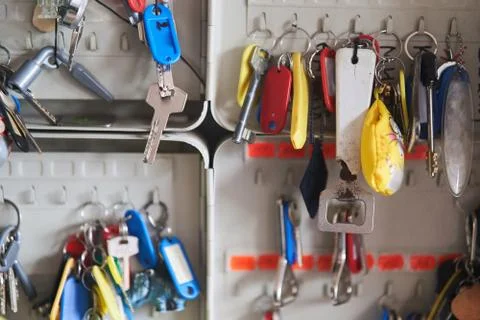 Many keys with multi-colored key chains hang in the key keeper Stock Photos