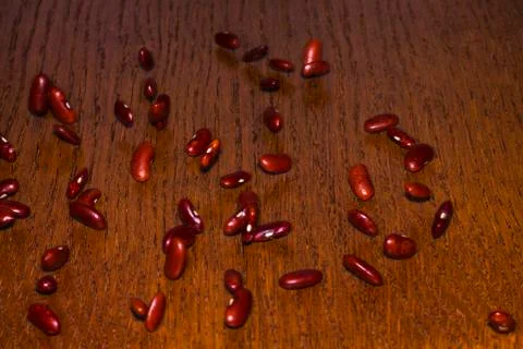 Many kidney beans roll down the wooden table. Stock Photos