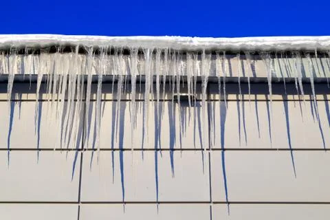 Many large and sharp icicles hang on the roof of the house. Foto stock